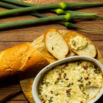 baguette on a board with a dish of leek scape dip