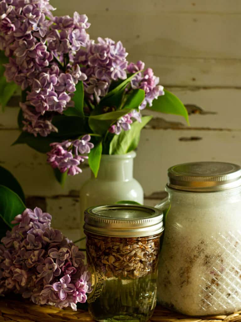 vase of lilacs with jars of lilac syrup and sugar