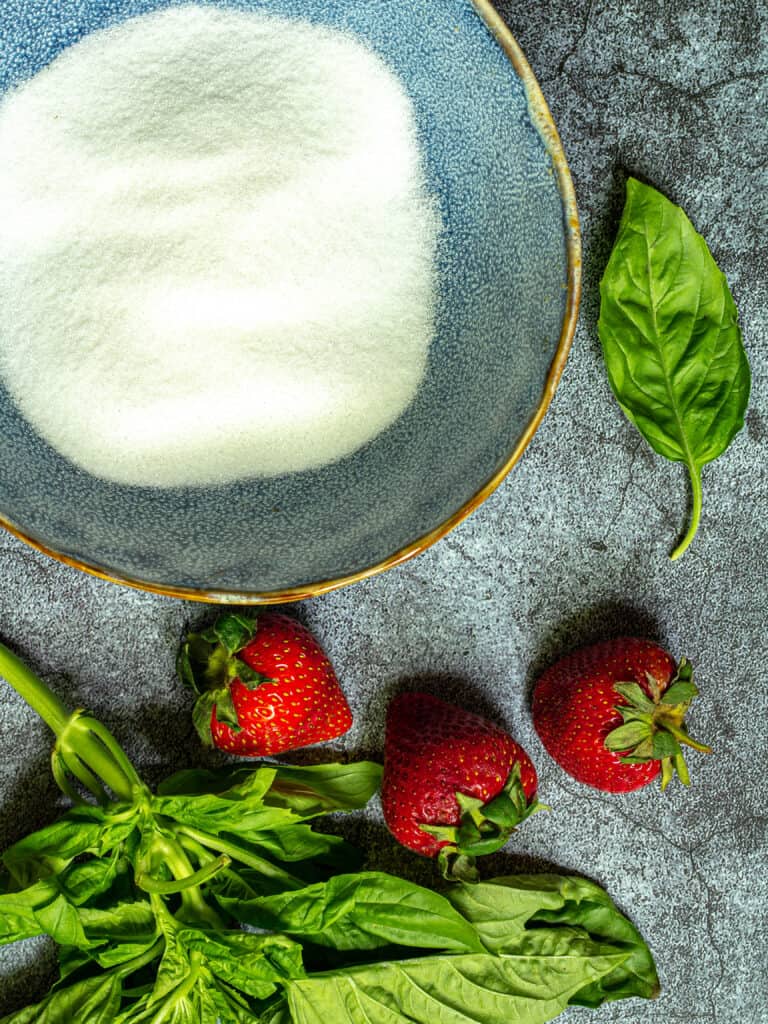 bowl of sugar with basil leaves and strawberries
