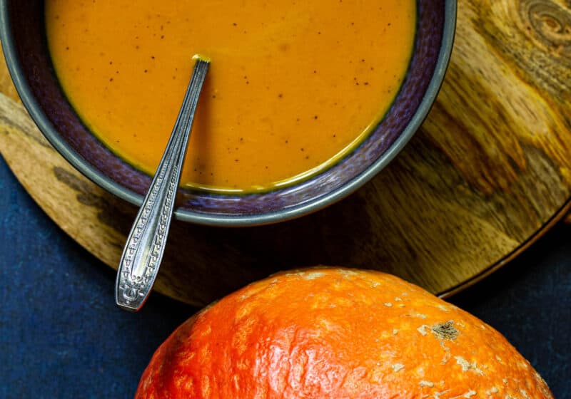 closeup photo of red kuri squash soup in a blue bowl