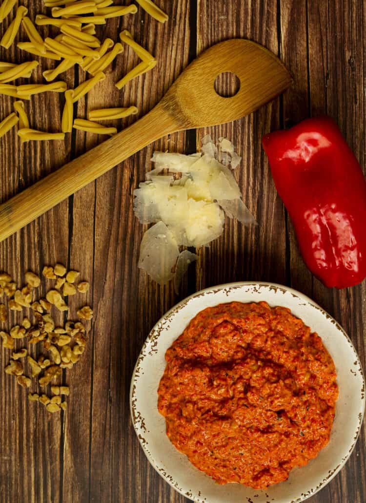 red pepper pesto with a wooden spoon and ingredients