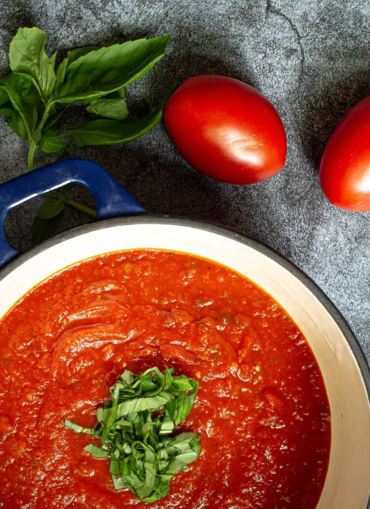 tomato sauce in a stock pot with fresh chopped basil
