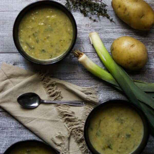bowls of leek and potato soup with a napkin and spoon