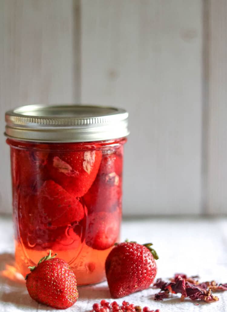 jar of pickled strawberries next to fresh srawberries
