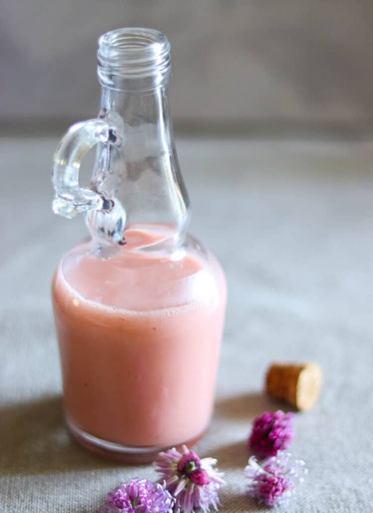 strawberry balsamic dressing in a glass bottle next to chive flowers