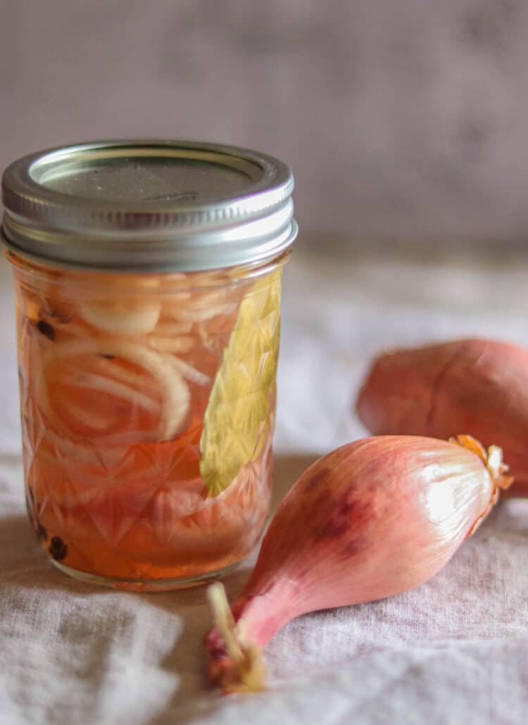 jar of pickled shallots next to a shallot.