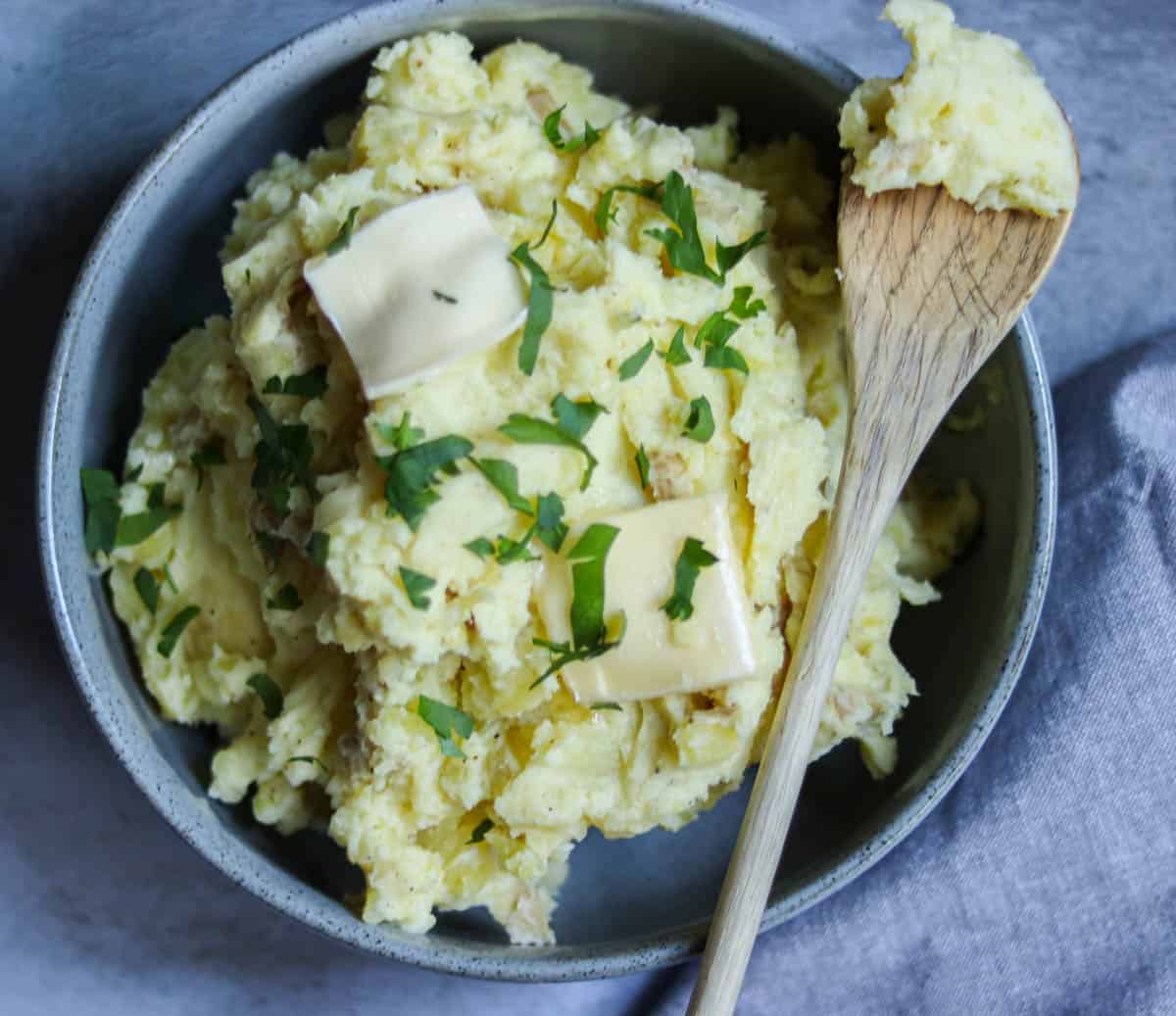 closeup photo of mashed potatoes topped with chopped parsley.
