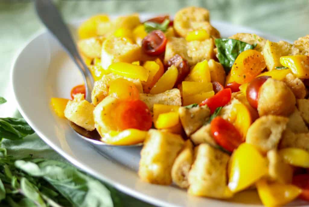 Closeup photo of Panzanella next to fresh basil leaves.