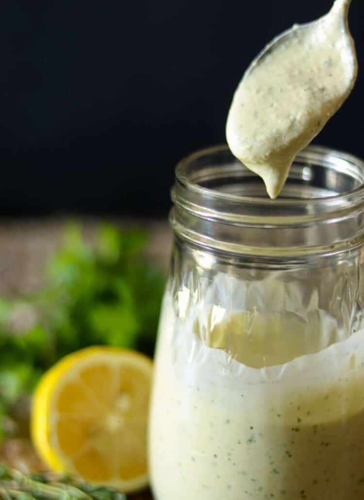 Lemon Herb Tahini Sauce in a jar with a spoon.