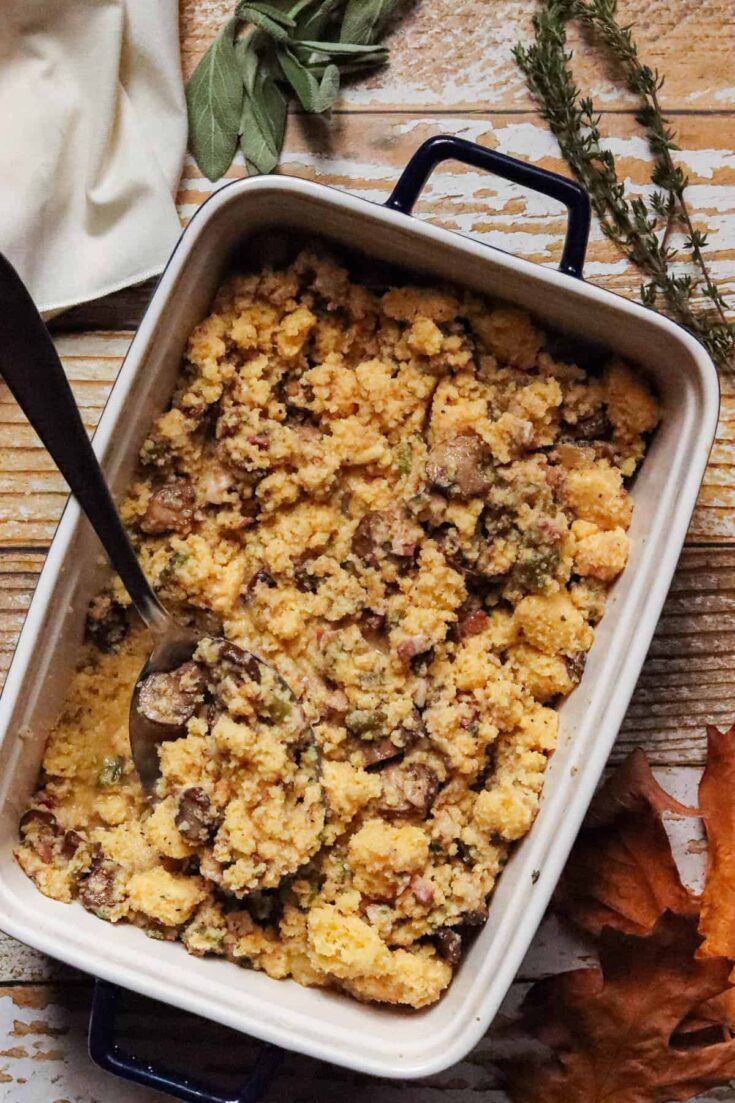 Cornbread dressing in a dish with a spoon.