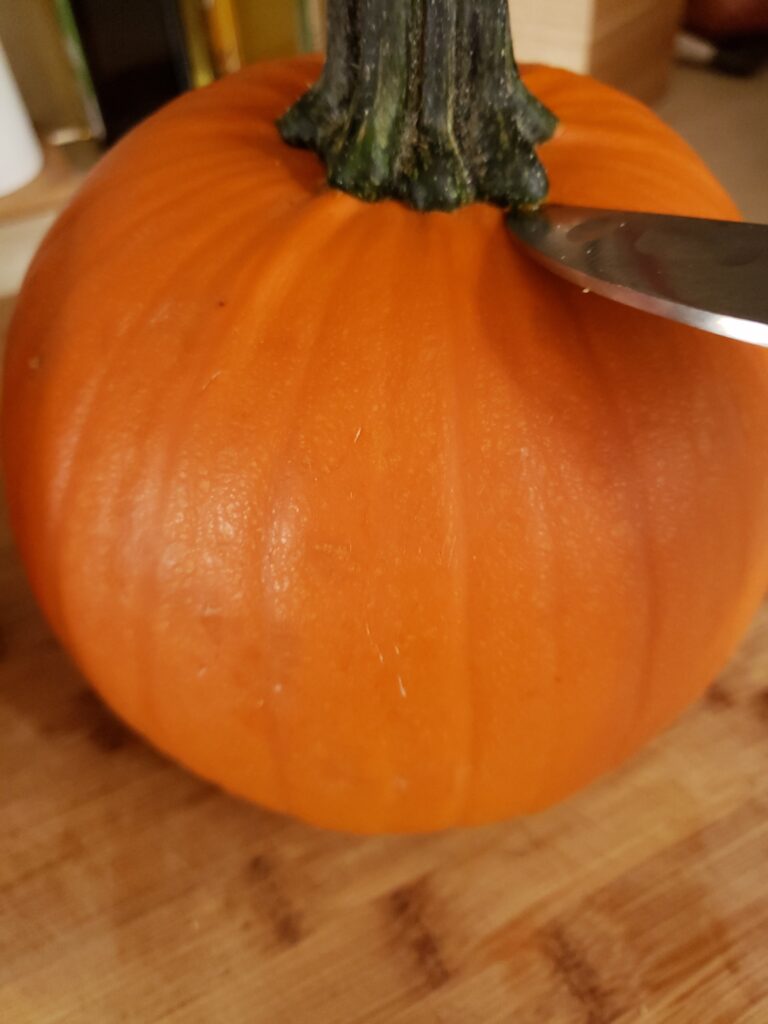 Using a knife to remove the pumpkin stem.