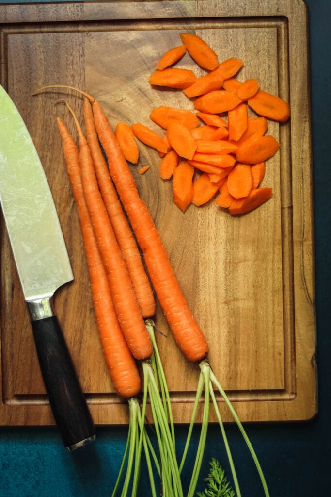 Carrots being sliced on a cutting board.