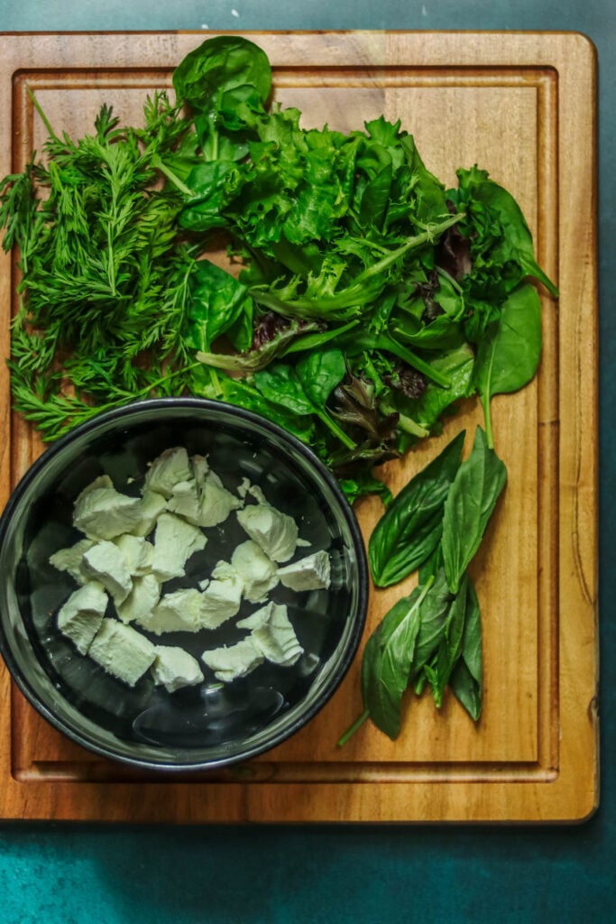 Goat cheese and Spring mix on a cutting board.