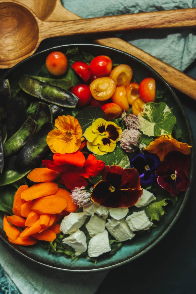 Bowl of salad with wooden utensils.