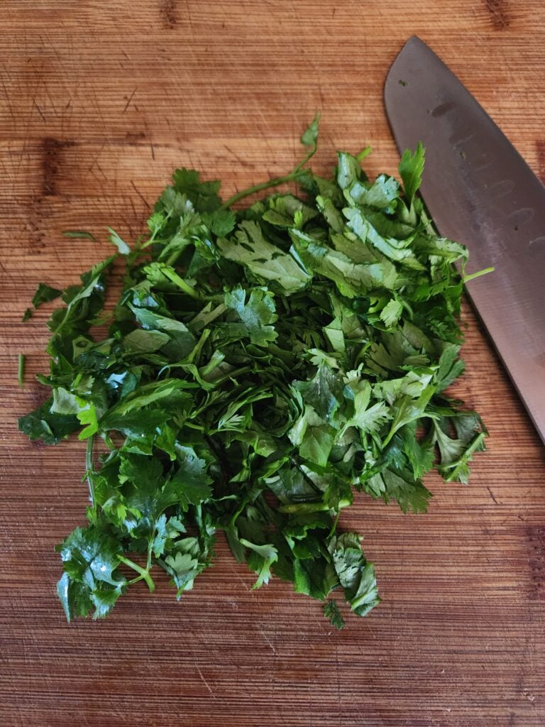 Chopped cilantro on a wood cutting board.