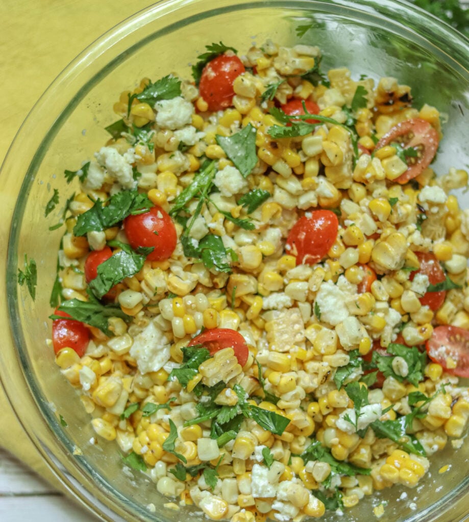 Grilled corn salad with tomatoes and cilantro in a glass bowl.