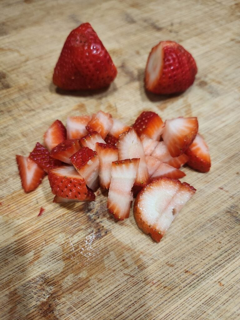 Chopped strawberries on a wood cutting board.