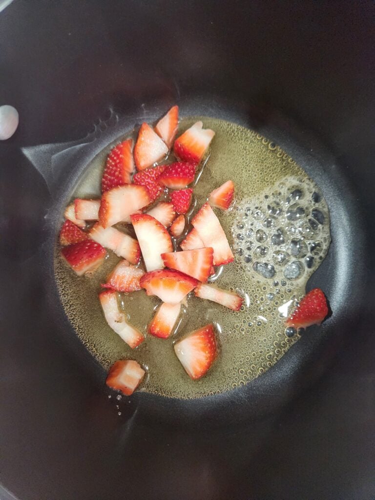 Honey and strawberries in a saucepan.