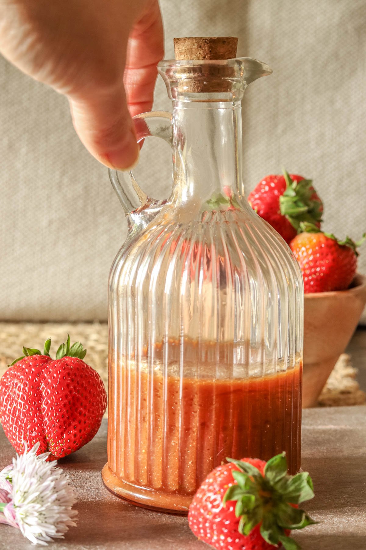 Bottle of strawberry vinaigrette being held by its handle.