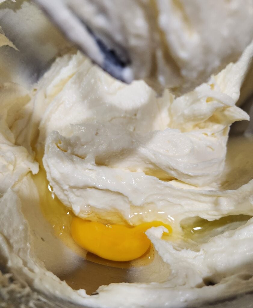 Adding the eggs to the mixer bowl.