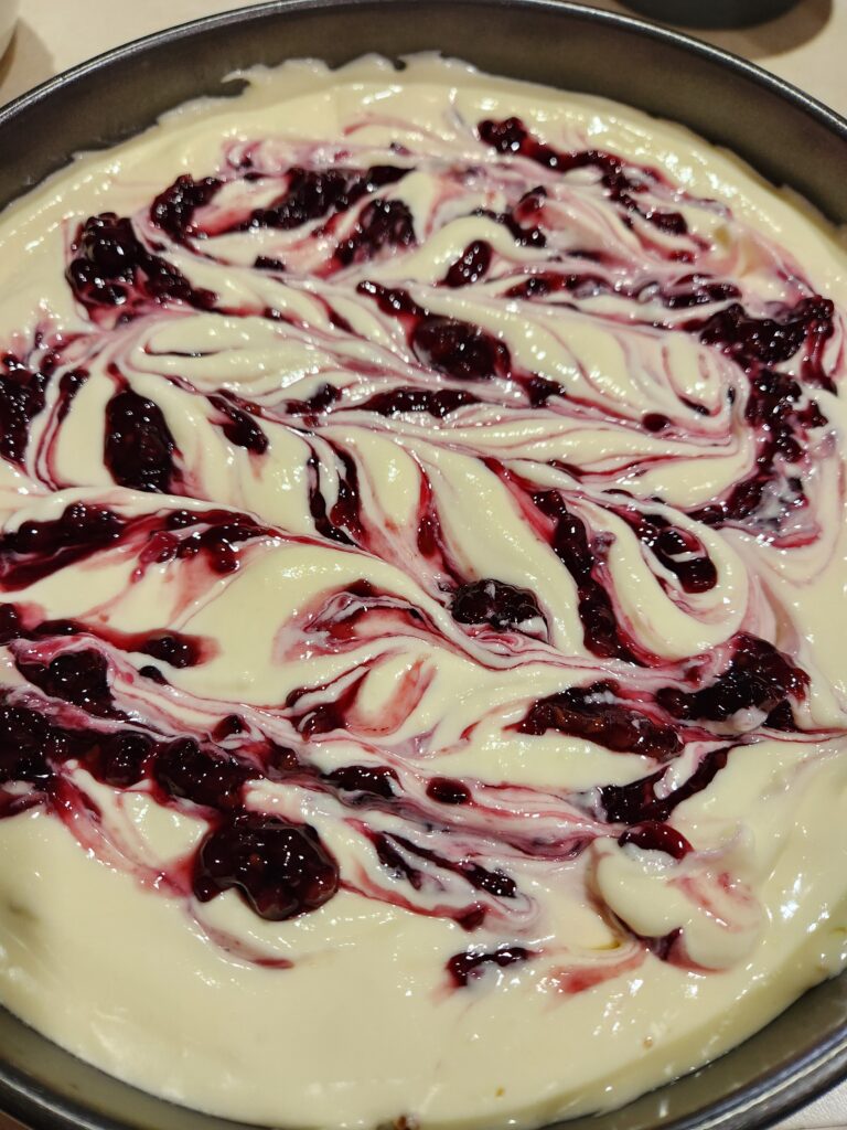 Cheesecake with blackberry sauce swirled on top.