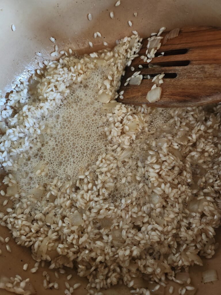 Adding hard cider to onions and rice.
