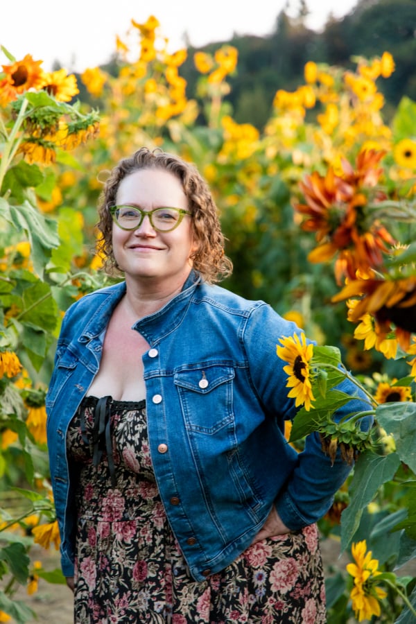 Amy, creator at The Copper Table standing in a field of sunflowers.
