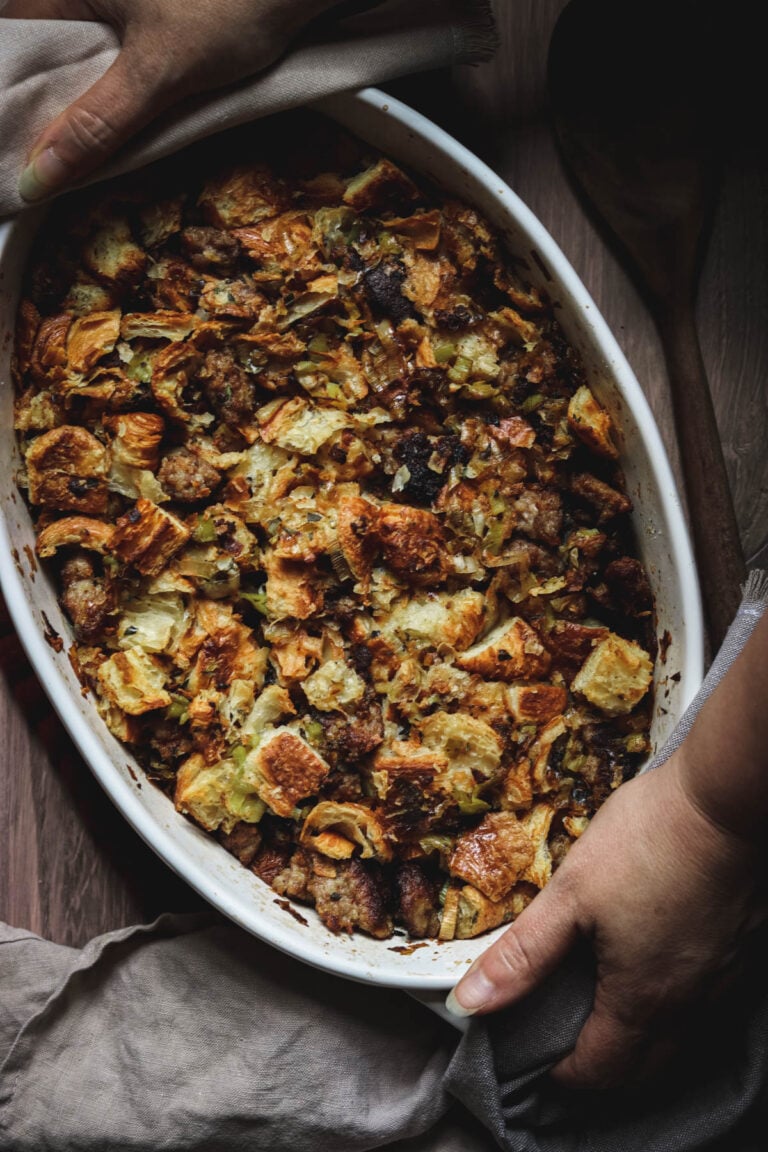 croissant stuffing in a casserole dish being placed on a table.