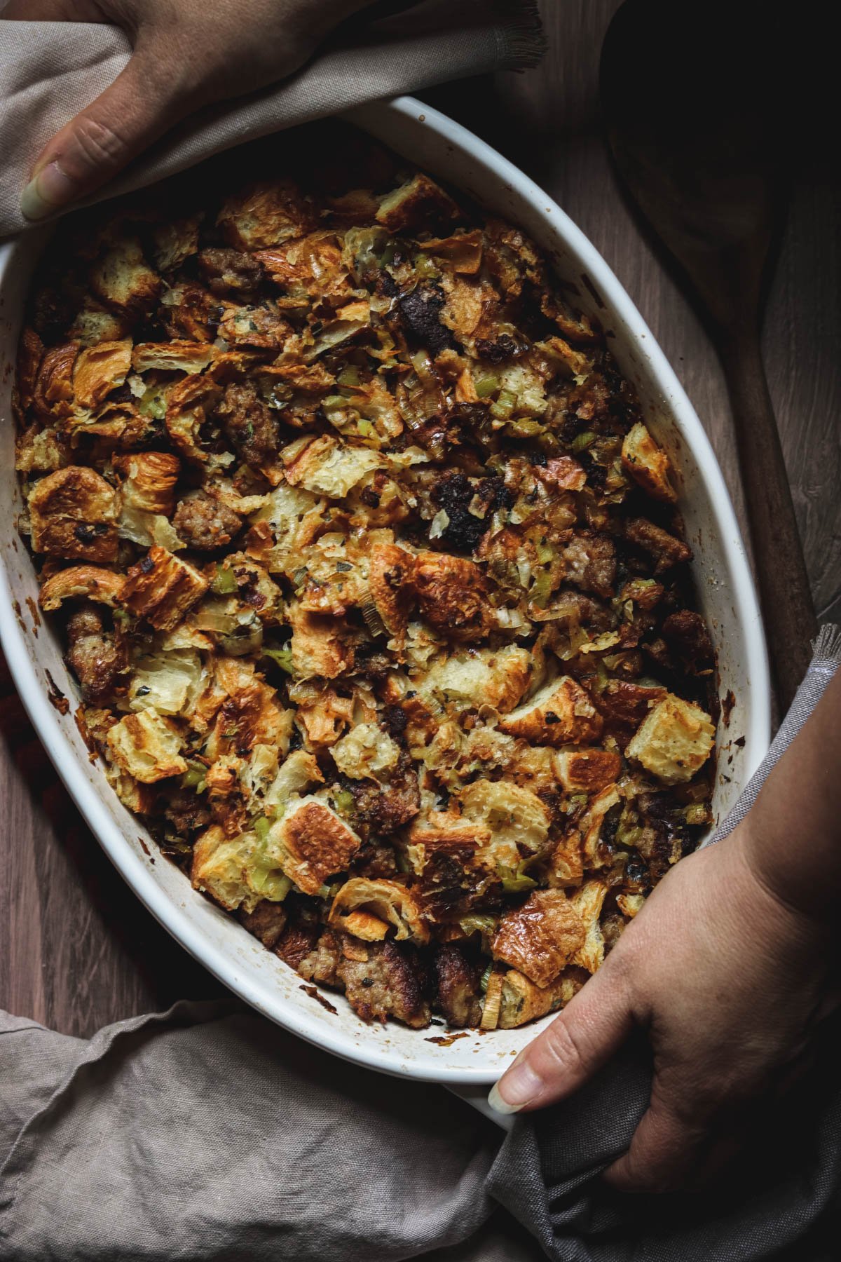 croissant stuffing in a casserole dish being placed on a table.