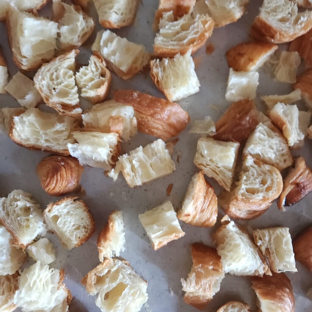 Cubed croissants on a baking sheet.