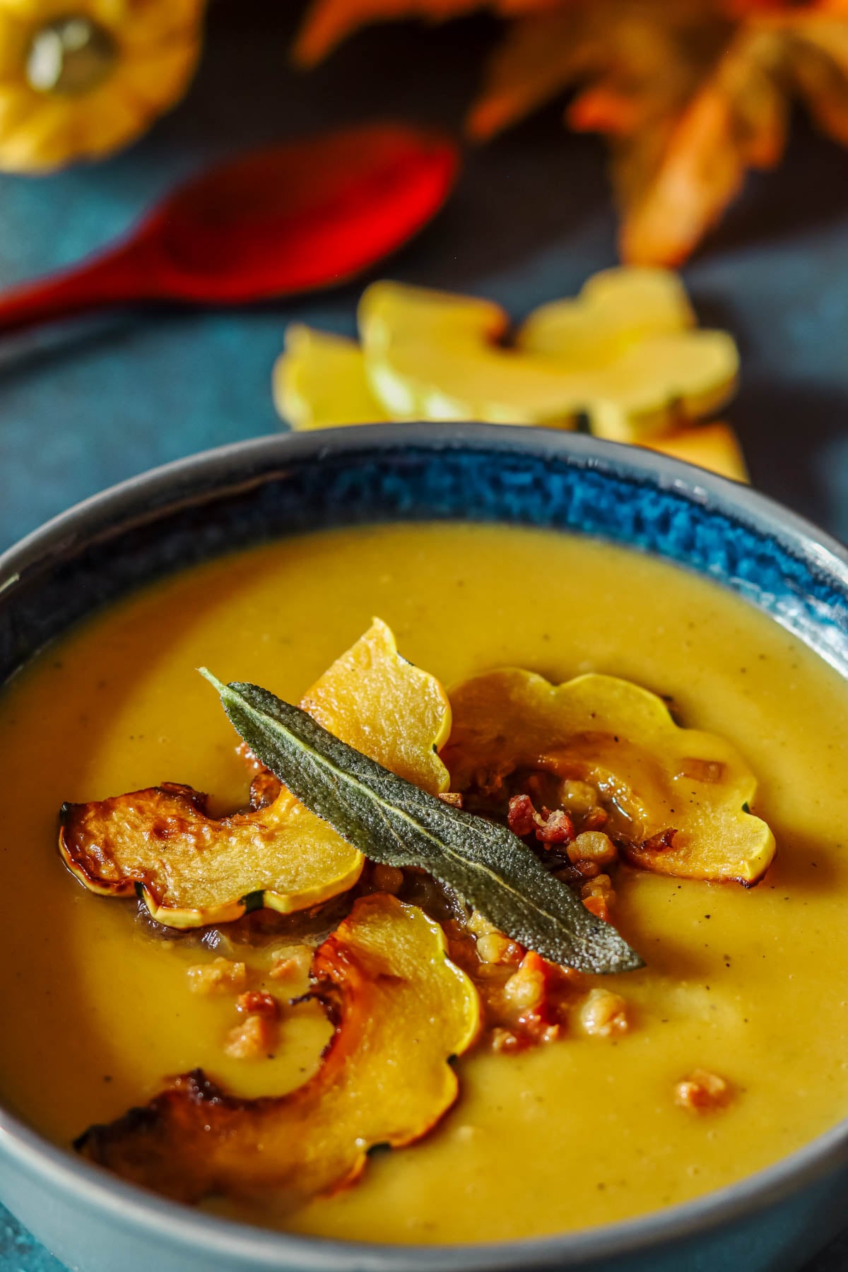 Delicata squash soup in a bowl on a blue background.