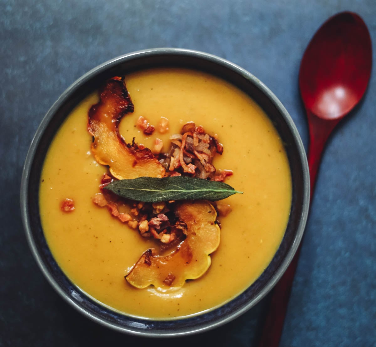 Roasted delicata squash soup with a wooden spoon.