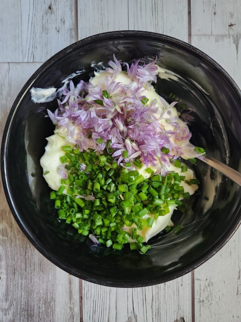 Adding the chives and chive blossoms to the butter.