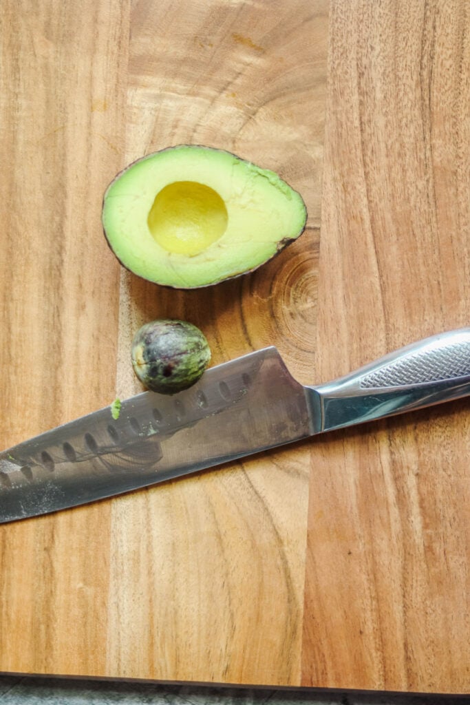 Avocado on a cutting board with the pit removed.