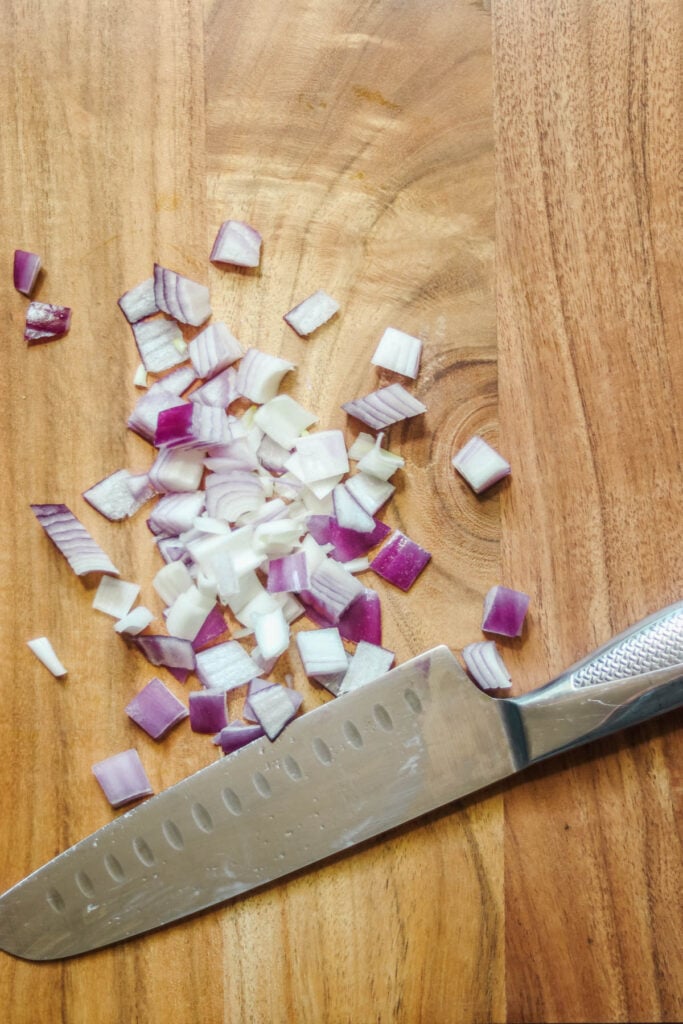 Diced red onion on a wood cutting board.