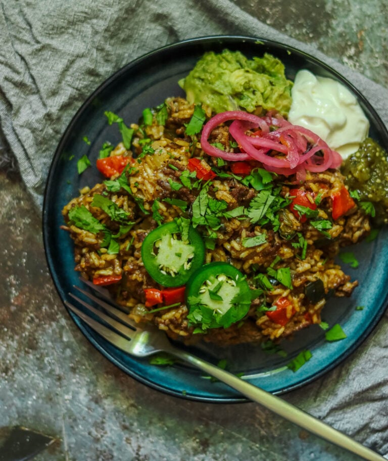 Beef taco rice on a blue plate with a fork.