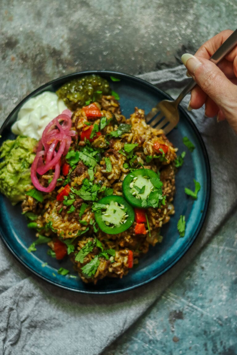 Taco skillet on a plate topped with jalapeno and cilantro.