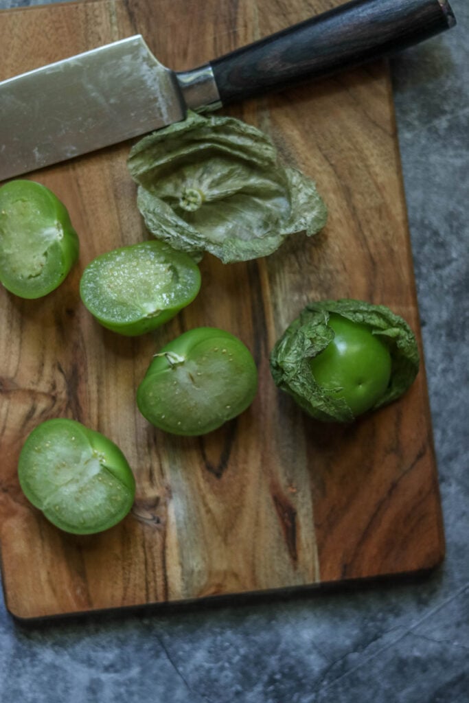 Tomatillos on a cutting board with a knife.