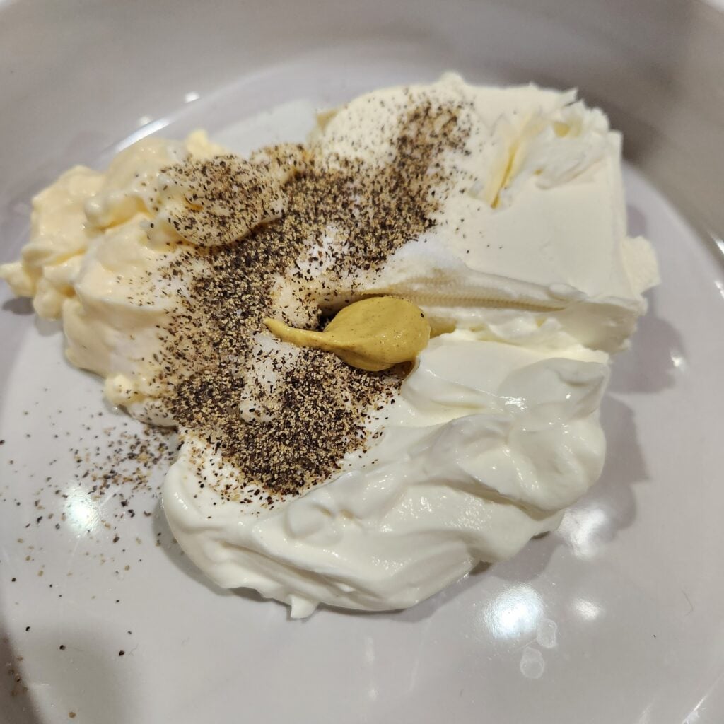 Cream cheese, mayo, and sour cream with seasonings in a baking dish.