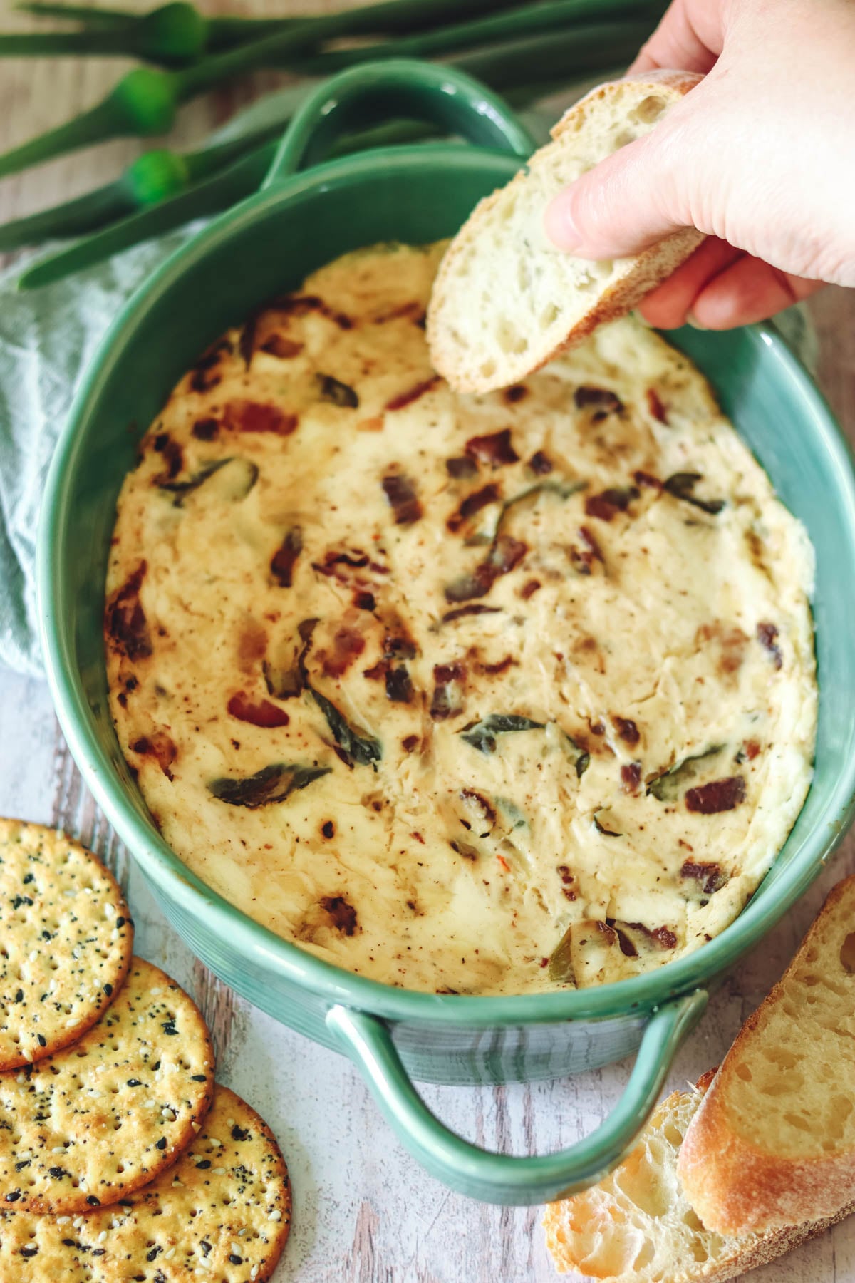 Bacon and cheese dip in a green oval baking dish.