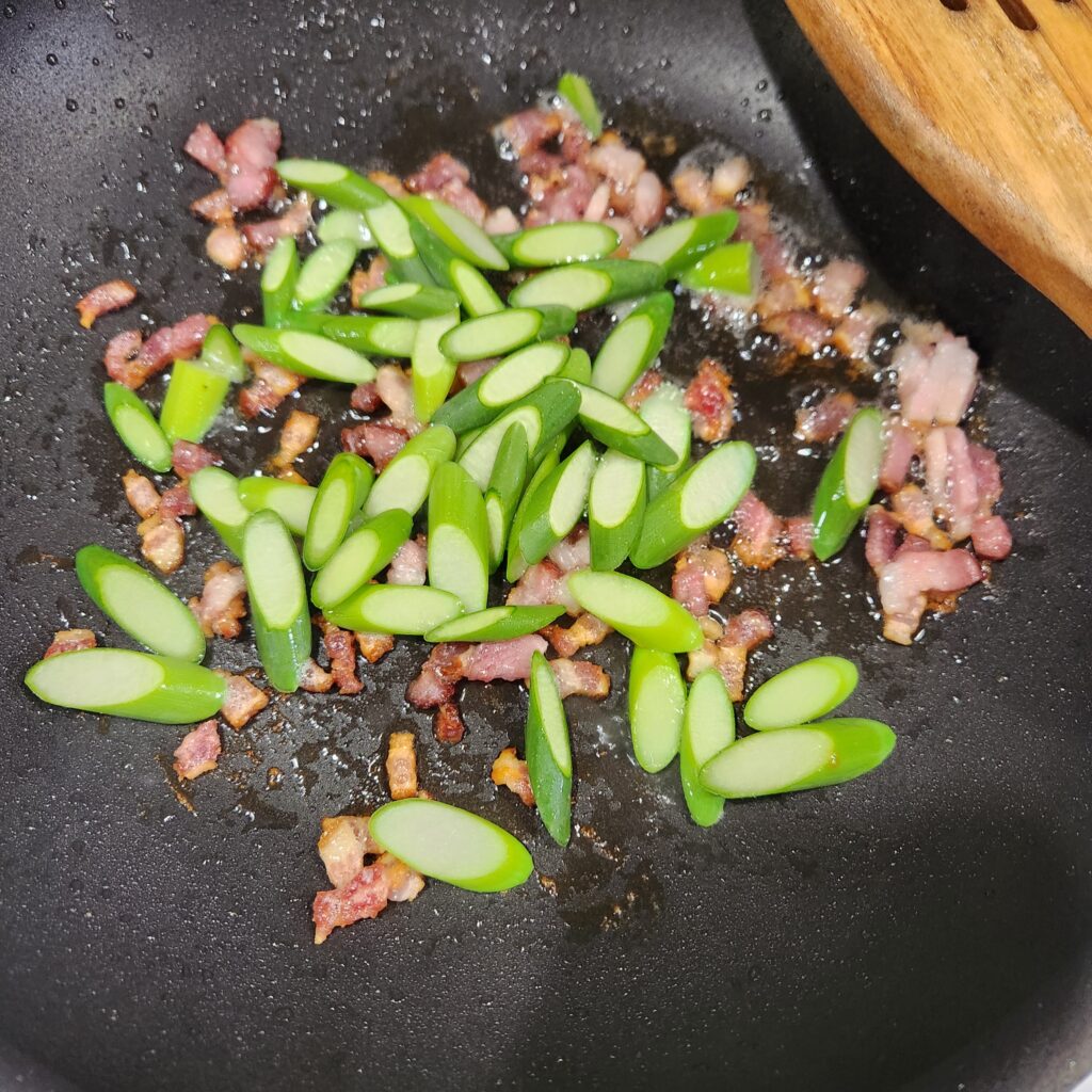 Cooking bacon and leek scapes.