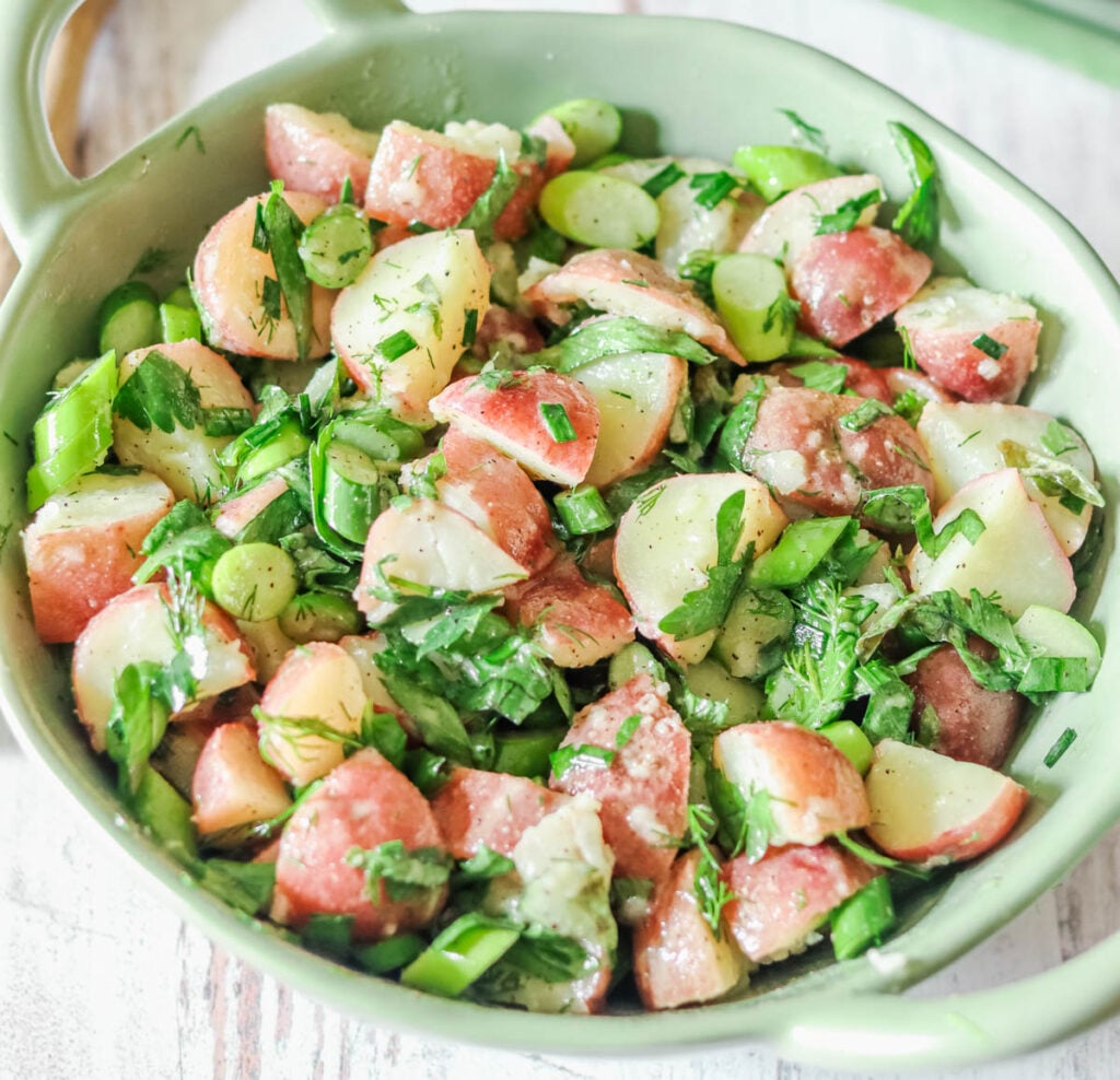 close up photo of spring potato salad in a green bowl.