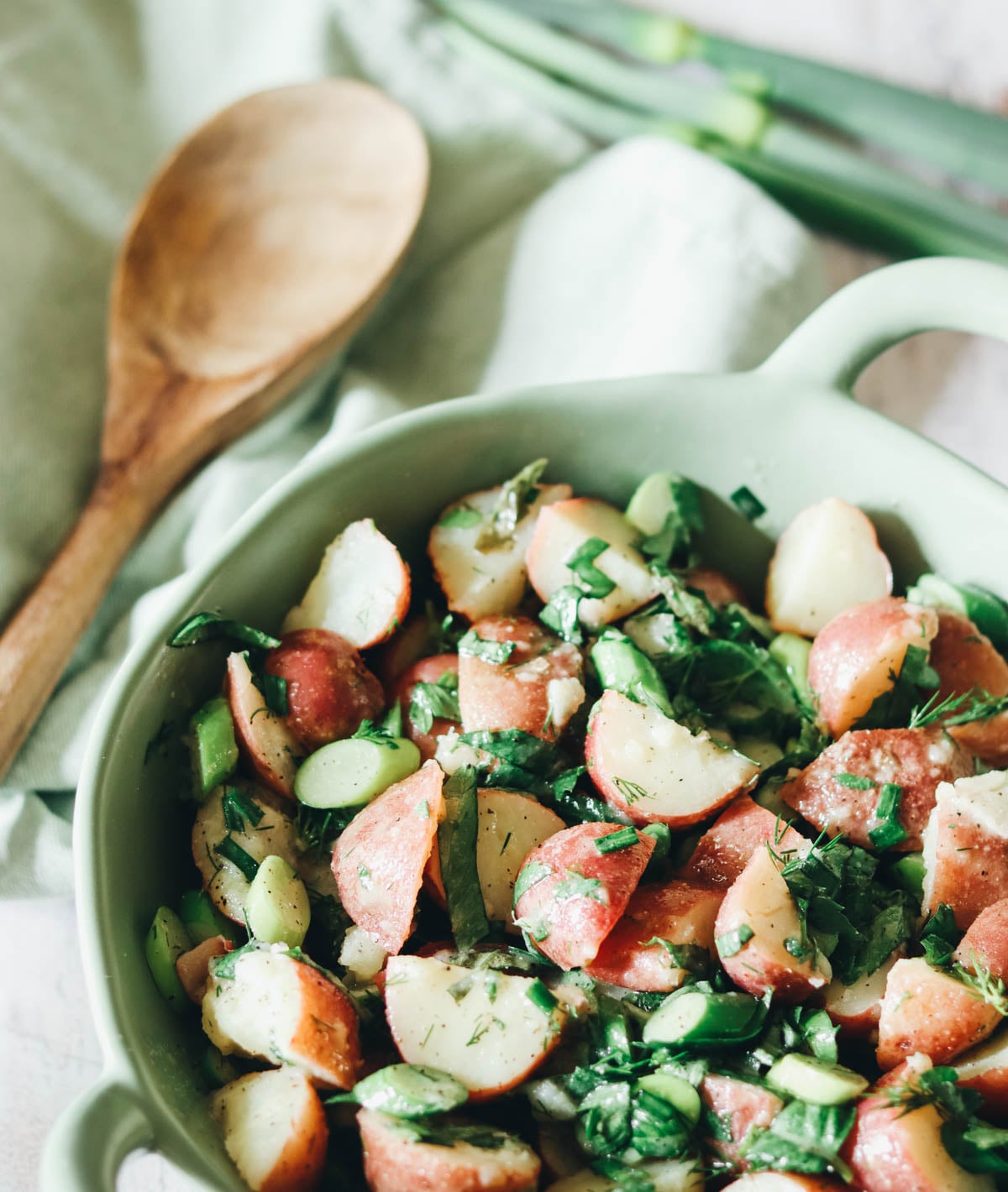 Vinaigrette potato salad in a bowl with a green napkin and spoon.